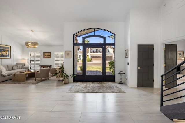 foyer entrance featuring a notable chandelier, high vaulted ceiling, and a healthy amount of sunlight