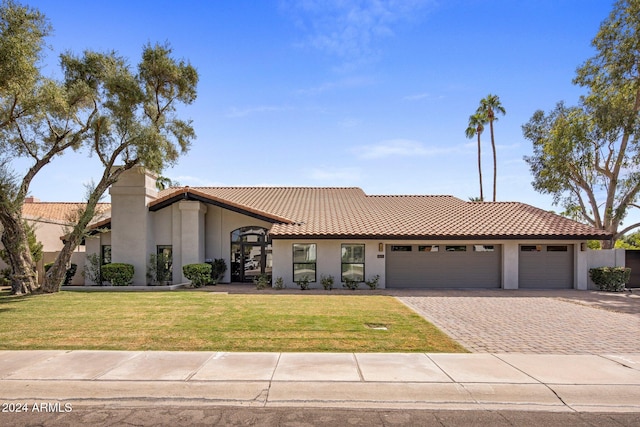 mediterranean / spanish-style house featuring a garage and a front lawn