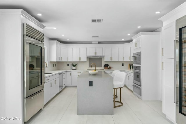 kitchen featuring stainless steel appliances, a kitchen island, white cabinets, and a kitchen breakfast bar