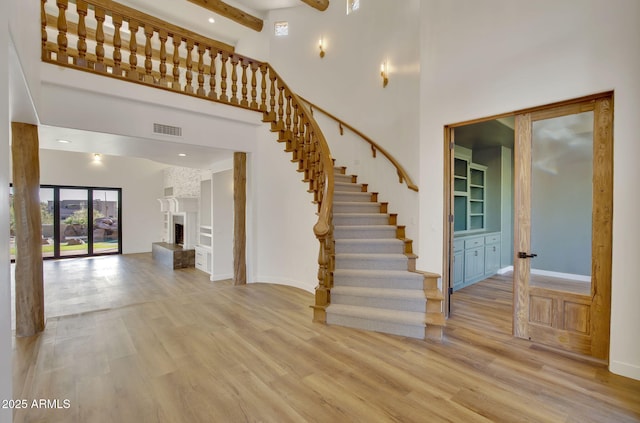 stairs with visible vents, a towering ceiling, baseboards, and wood finished floors