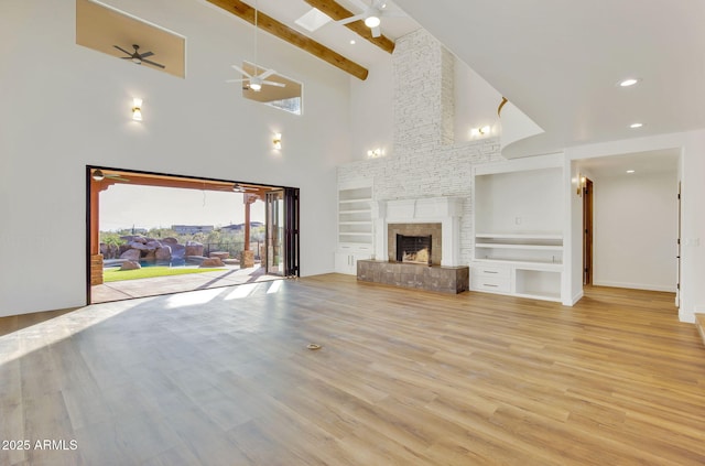 unfurnished living room with high vaulted ceiling, a ceiling fan, built in features, light wood-style flooring, and a fireplace