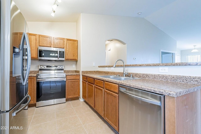 kitchen with sink, kitchen peninsula, lofted ceiling, light tile patterned floors, and appliances with stainless steel finishes