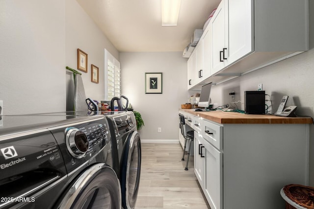 washroom featuring light hardwood / wood-style floors, cabinets, and washing machine and clothes dryer