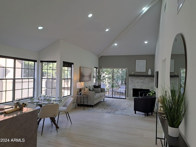 interior space with a fireplace, high vaulted ceiling, and light hardwood / wood-style flooring