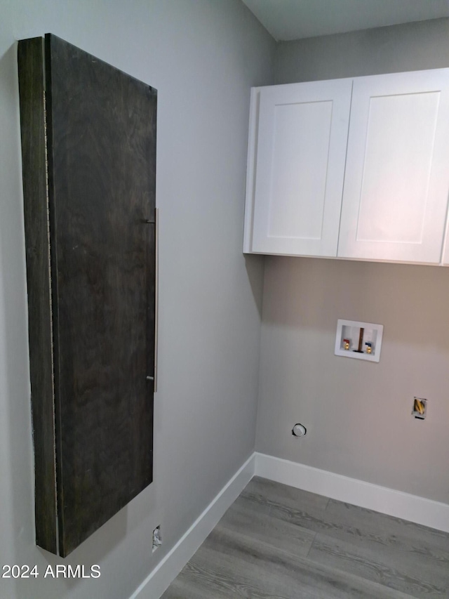 laundry area with washer hookup, cabinets, and light wood-type flooring