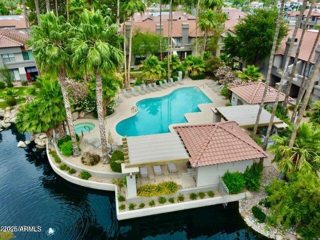 view of pool with a patio area, a water view, and a hot tub