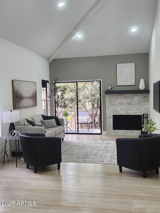 living room with lofted ceiling with beams, light hardwood / wood-style floors, and a fireplace