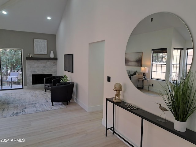 corridor with high vaulted ceiling and light hardwood / wood-style flooring