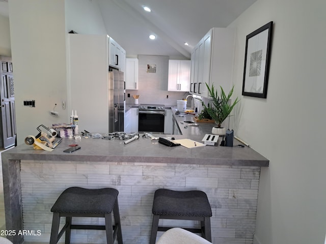 kitchen featuring kitchen peninsula, stainless steel appliances, beamed ceiling, white cabinets, and a breakfast bar area