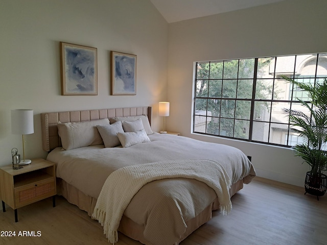 bedroom with light wood-type flooring and vaulted ceiling