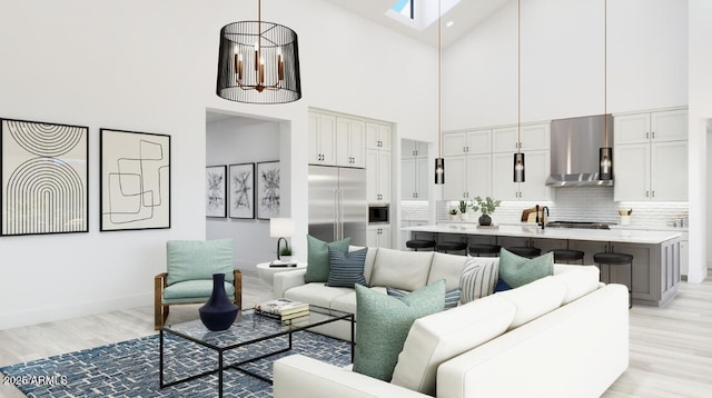 living area with a skylight, baseboards, light wood finished floors, and a towering ceiling