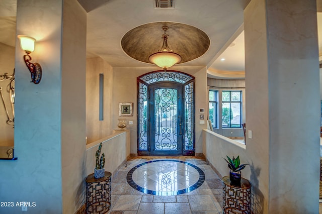 entryway featuring a tray ceiling and ornamental molding