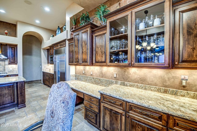 kitchen with light tile floors, backsplash, extractor fan, and light stone counters