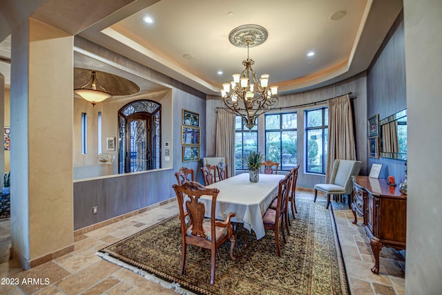tiled dining area with an inviting chandelier and a tray ceiling