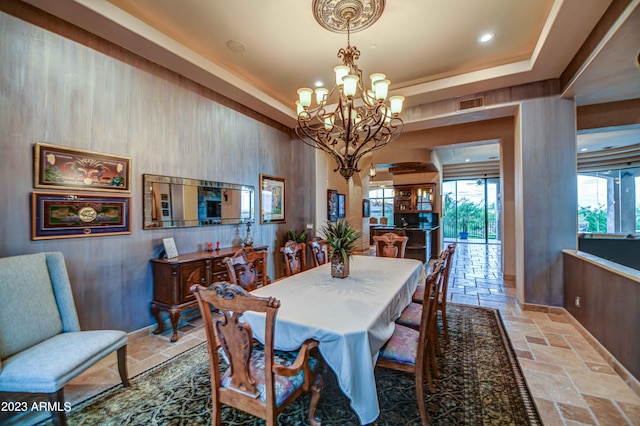 dining room with an inviting chandelier, a tray ceiling, and tile floors