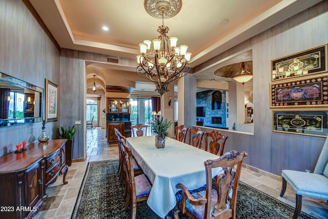 dining room with a chandelier, light tile flooring, and a raised ceiling