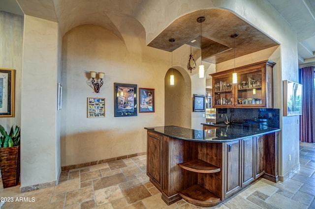 bar featuring sink, dark stone counters, light tile flooring, and pendant lighting