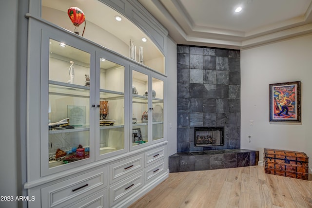 living room featuring a fireplace, tile walls, a tray ceiling, and wood-type flooring
