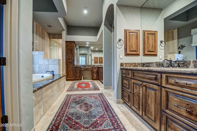 bathroom featuring tile flooring, vanity, and tiled tub