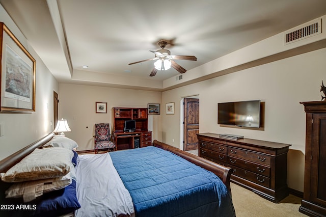 carpeted bedroom with a raised ceiling and ceiling fan