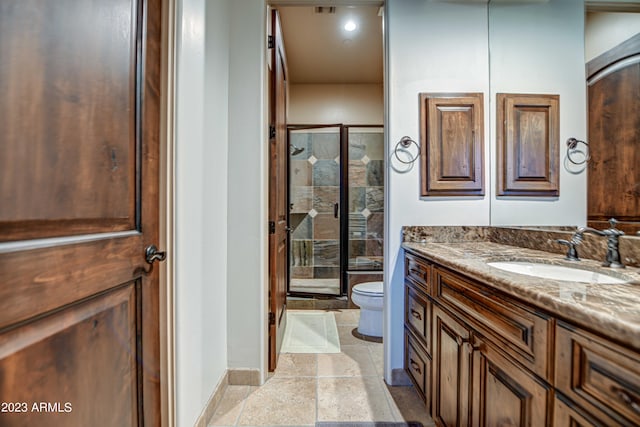 bathroom with toilet, a shower with shower door, large vanity, and tile flooring