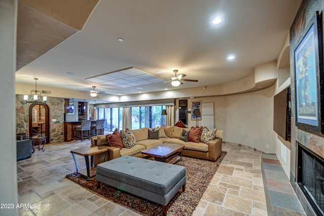 tiled living room featuring ceiling fan with notable chandelier