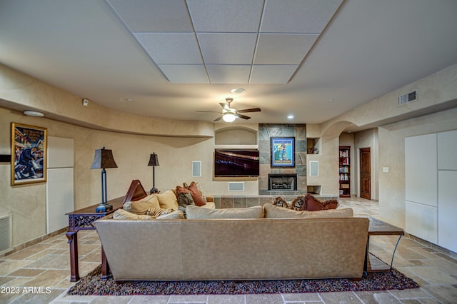 tiled living room with ceiling fan and a tile fireplace