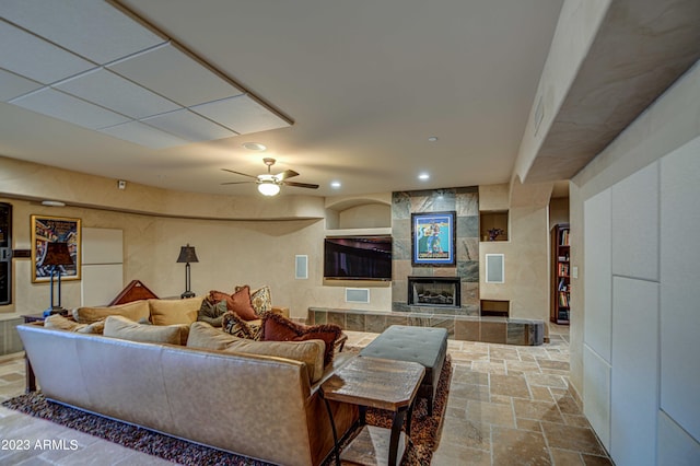 living room featuring light tile flooring, ceiling fan, and a tiled fireplace