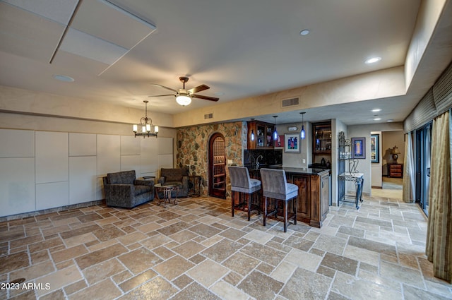 kitchen featuring hanging light fixtures, light tile floors, a breakfast bar, and ceiling fan with notable chandelier