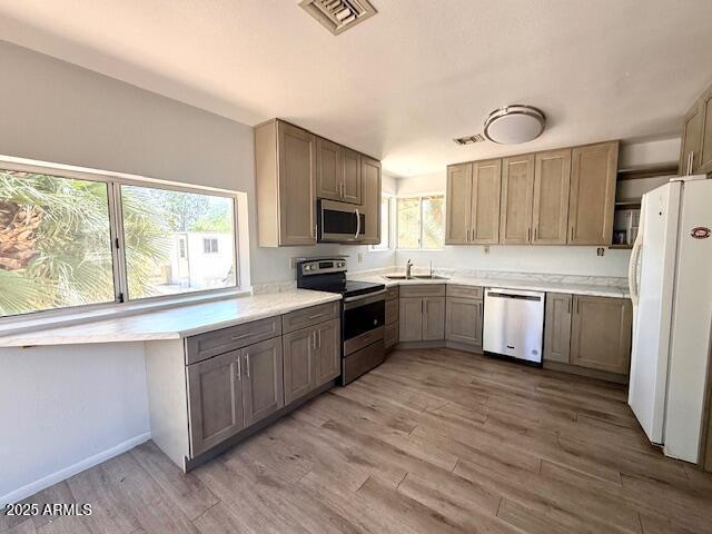 735 E Desert Ave, Apache Junction, AZ 85119 - kitchen featuring stainless steel appliances, a sink, light wood-style floors, light countertops, and baseboards