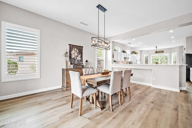 dining room featuring light hardwood / wood-style flooring, a healthy amount of sunlight, and a notable chandelier