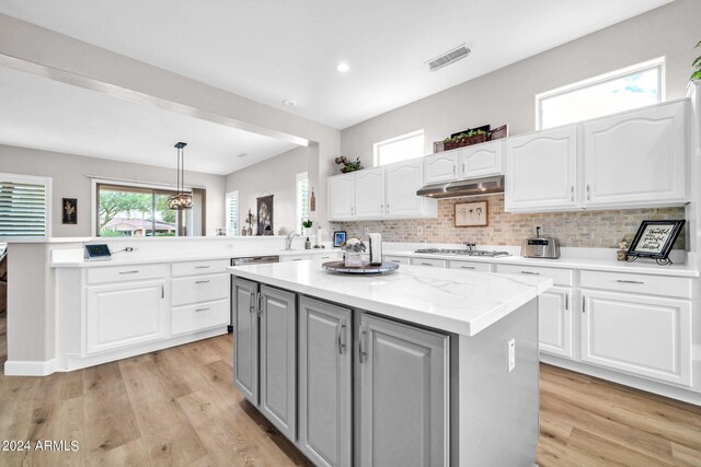 kitchen featuring a kitchen island, white cabinets, pendant lighting, and light hardwood / wood-style floors