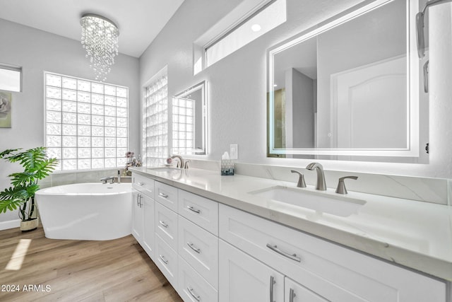 bathroom featuring vanity, a notable chandelier, hardwood / wood-style flooring, and a washtub