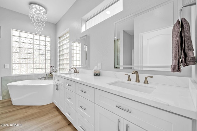 bathroom featuring vanity, hardwood / wood-style flooring, a chandelier, and a bathtub