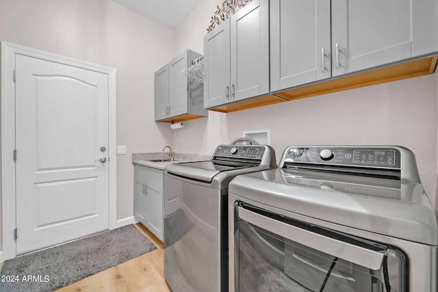 washroom with light hardwood / wood-style floors, cabinets, and washer and clothes dryer