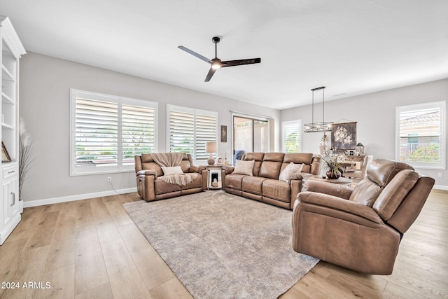 living room featuring ceiling fan with notable chandelier, light wood-type flooring, and a healthy amount of sunlight