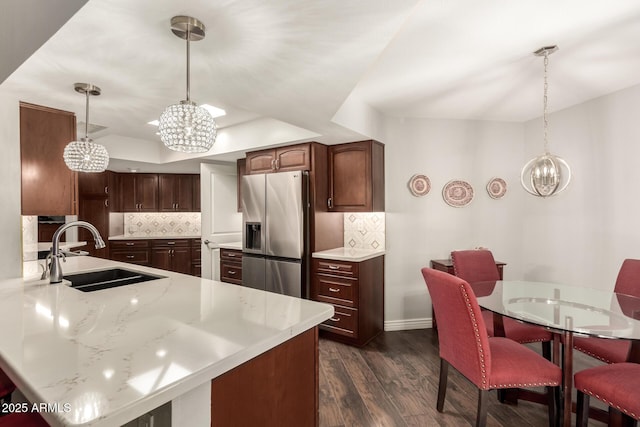 kitchen featuring sink, tasteful backsplash, hanging light fixtures, stainless steel fridge with ice dispenser, and a chandelier