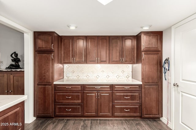 kitchen with dark wood-type flooring, light stone countertops, and tasteful backsplash