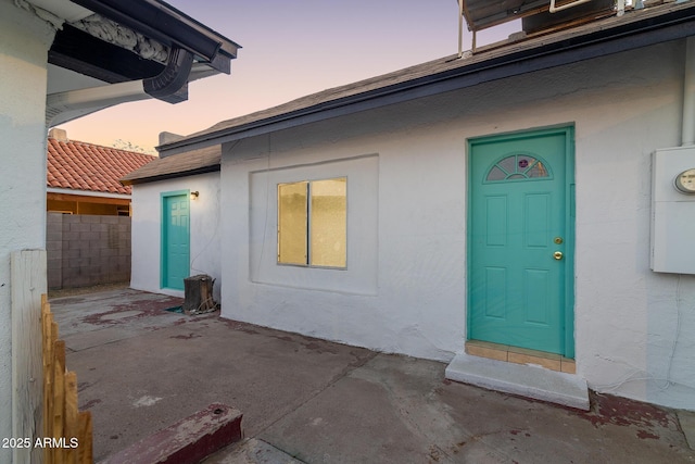 exterior entry at dusk featuring a patio