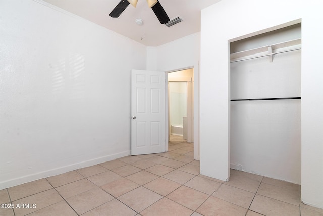 unfurnished bedroom with light tile patterned flooring, ceiling fan, crown molding, and a closet