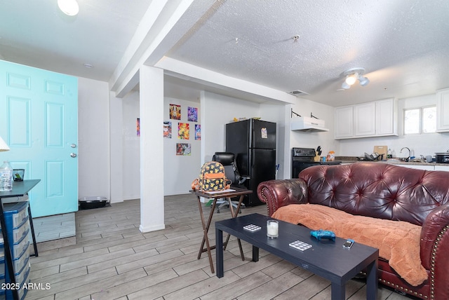 living room featuring sink and a textured ceiling