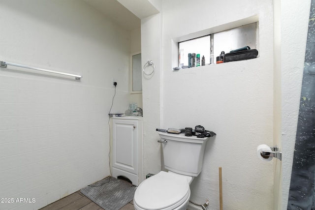 bathroom featuring tile walls, wood-type flooring, and toilet