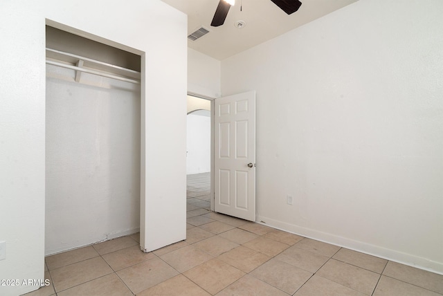 unfurnished bedroom with light tile patterned floors, a closet, and ceiling fan