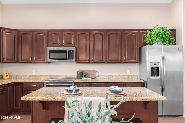 kitchen featuring light stone counters, stainless steel appliances, a center island, and tile patterned flooring