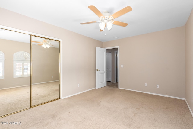 unfurnished bedroom with light carpet, a closet, and ceiling fan