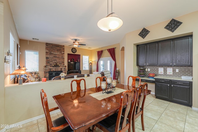 2115 N Cougar Ct, Casa Grande, AZ 85122 - dining room with a stone fireplace, light tile patterned floors, a ceiling fan, visible vents, and arched walkways