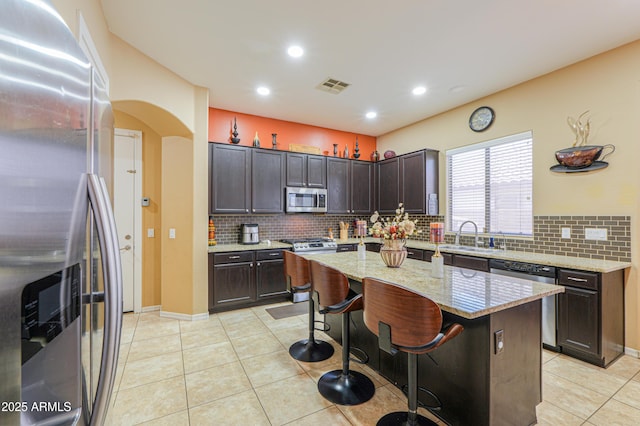 2115 N Cougar Ct, Casa Grande, AZ 85122 - kitchen with dark brown cabinetry, visible vents, a kitchen bar, stainless steel appliances, and arched walkways