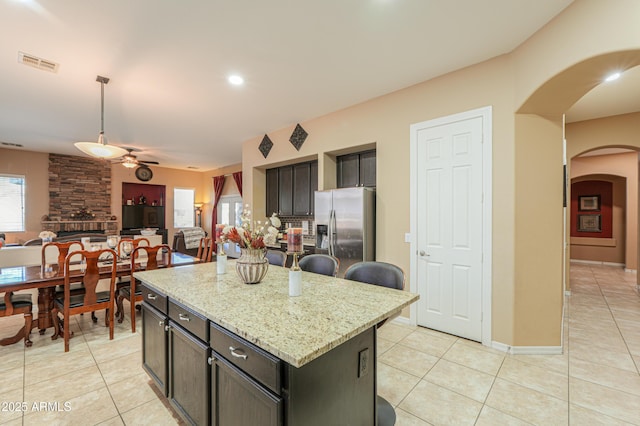 2115 N Cougar Ct, Casa Grande, AZ 85122 - kitchen featuring stainless steel fridge with ice dispenser, visible vents, light tile patterned floors, arched walkways, and ceiling fan