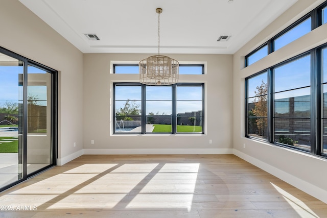 unfurnished dining area with a healthy amount of sunlight, light hardwood / wood-style floors, and a chandelier