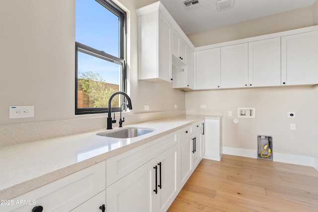 washroom with hookup for an electric dryer, a healthy amount of sunlight, sink, and washer hookup